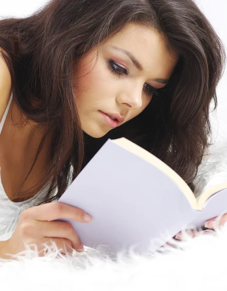 Mladá atraktivní žena leží na posteli s knihou — Stock fotografie