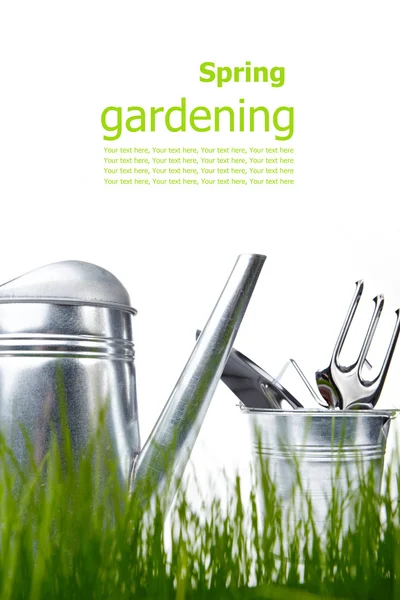 Outils de jardin et arrosoir avec herbe sur blanc — Photo