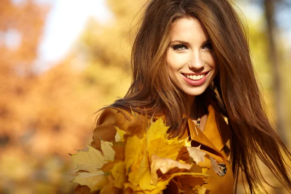 Junge Frau in herbstorangefarbenen Blättern. Außenbereich. — Stockfoto