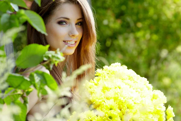 Szczęśliwy uśmiechający się młoda kobieta z bukiet kwiatów na zielony żółty — Zdjęcie stockowe