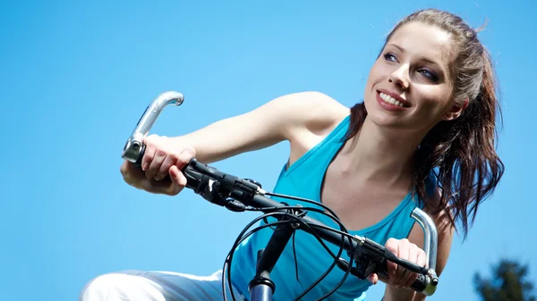 Woman with bike under blue skies — Stock Photo, Image