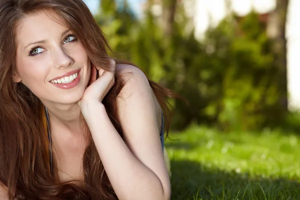 Beautiful young woman sitting in the grass — Stock Photo, Image