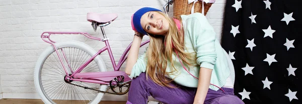 Ung kvinna med rosa cykel hemma — Stockfoto