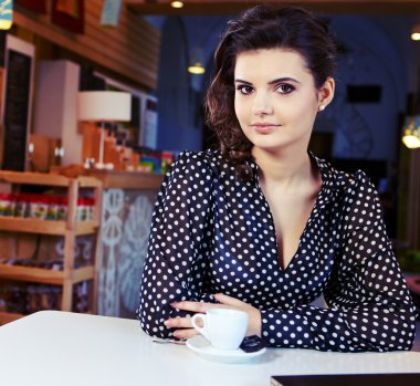 sevimli seksi kadın siyah giysiler içinde muhteşem bir kafede oturuyor