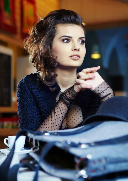 Okouzlující sexy žena v černých šatech sedí na velkolepé café — Stock fotografie