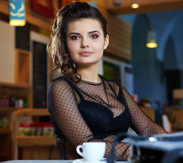 Affascinante donna sexy in vestiti neri si siede al magnifico caffè — Foto Stock