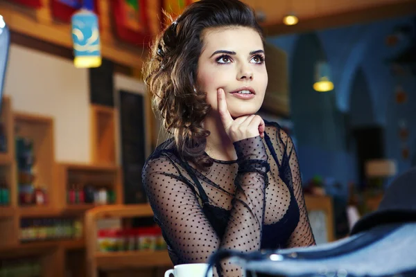 Sevimli seksi kadın siyah giysiler içinde muhteşem bir kafede oturuyor — Stok fotoğraf