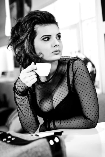 Encantadora mujer sexy en ropa negra se sienta en la magnífica cafetería — Foto de Stock