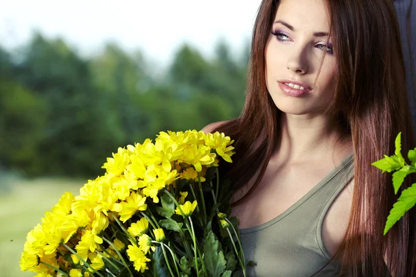 可爱的年轻女孩与黄色的花朵微笑的特写肖像 — 图库照片
