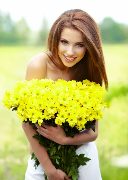 Closeup portrait of cute young girl with yellow flowers smiling — Zdjęcie stockowe