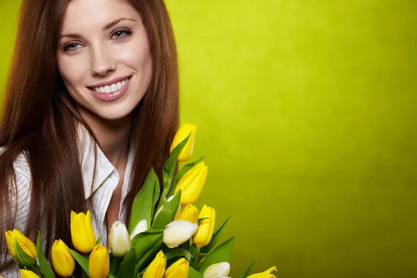 Lächelndes Mädchen mit gelben Tulpen. grüner Hintergrund — Stockfoto