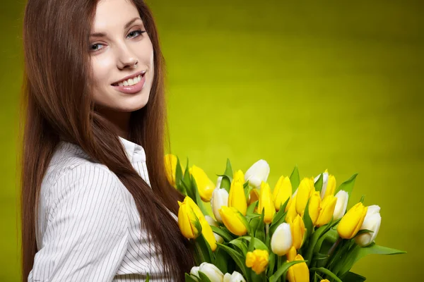 Lachende meisje met gele tulpen. groene achtergrond — Stockfoto