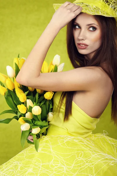 stock image Young woman hold yellow tulips flower on green