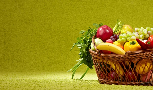 Fresh vegetables in basket on green background — Stock Photo, Image