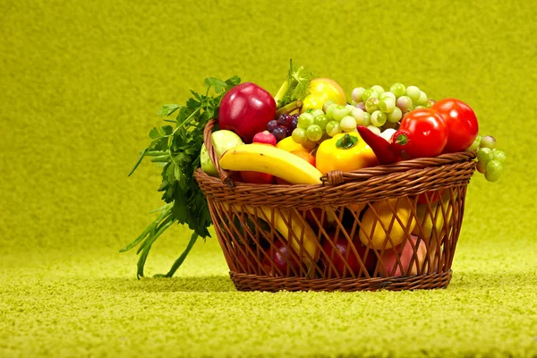 Fresh vegetables in basket on green background — Stock Photo, Image