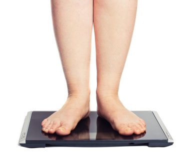 Bare female feet standing on bathroom scale clipart