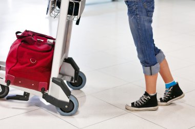 Woman's legs and feet with luggage cart with bag clipart