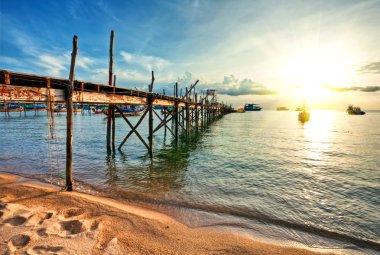 Wooden pier and boats in sunset lights clipart