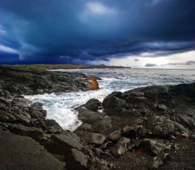 Volcanic stonesl beach under gloomy sky clipart