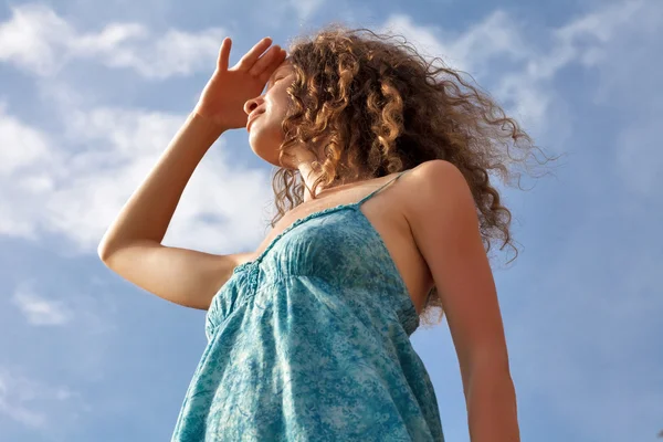 Ung kvinna på blå himmel bakgrund — Stockfoto