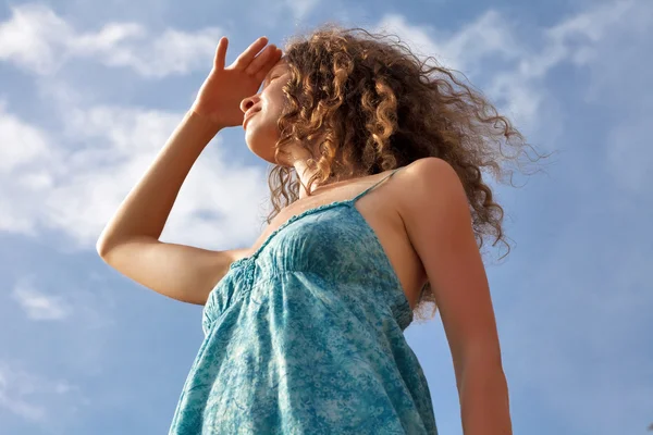 Young woman on blue sky background — Stock Photo, Image