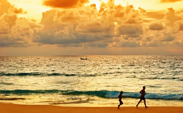 Jeunes courses à la plage au coucher du soleil — Photo