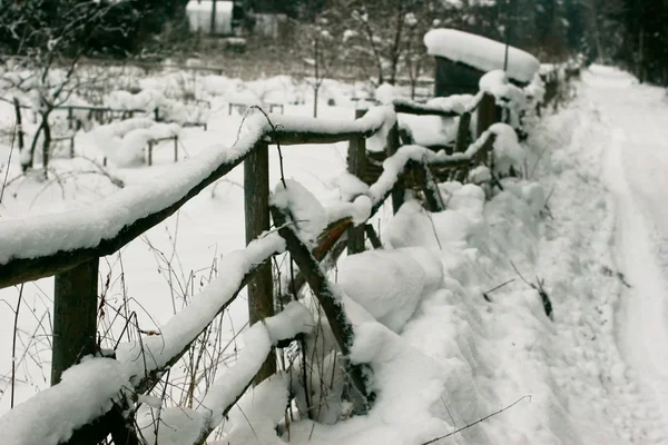 A velha cerca de madeira nos bonés de neve — Fotografia de Stock