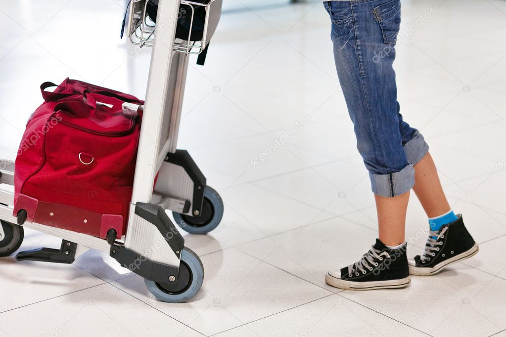 Woman's legs and feet with luggage cart with bag