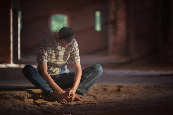 Продуманий чоловік сидить на піску Ліцензійні Стокові Фото