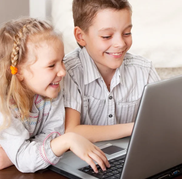 Crianças felizes jogando laptop em casa — Fotografia de Stock