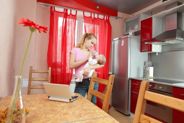 Νεαρή μητέρα στην κουζίνα με το φορητό υπολογιστή — Φωτογραφία Αρχείου