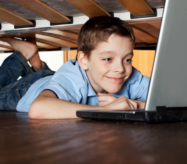 Yatağın altında laptop oynayan çocuk — Stok fotoğraf