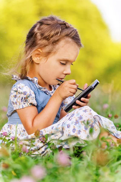 Kleines Mädchen schreibt Stift auf Gerät — Stockfoto