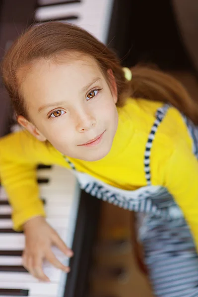Little girl in yellow dress plays piano — Stock Photo, Image