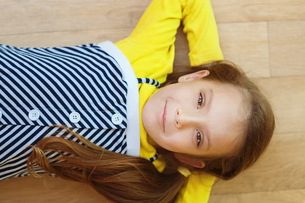 Little girl in yellow dress lying on floor — Stock Photo, Image
