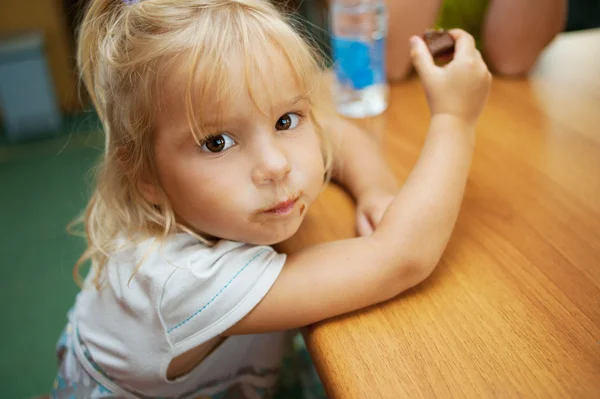 Kleines Mädchen isst Schokoriegel — Stockfoto