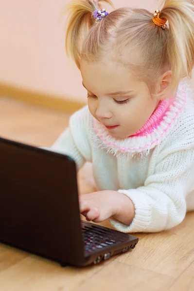 Kleines Mädchen im weißen Pullover auf dem Boden liegend — Stockfoto