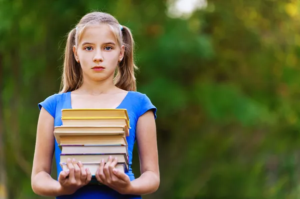 Девочка-подросток держит стопку из семи книг — стоковое фото