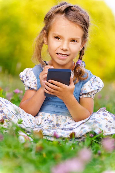 Little girl writes stylus on device — Stock Photo, Image