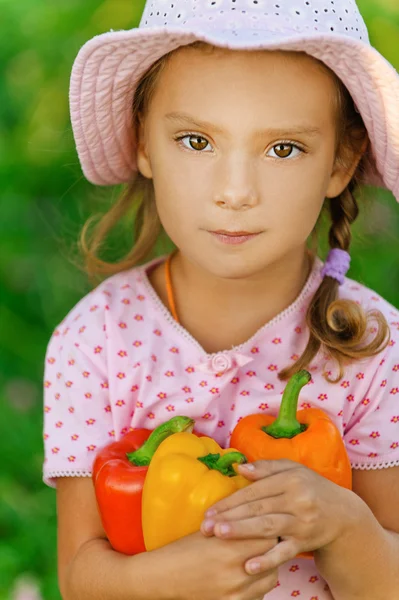 Маленькая девочка в шляпе держит перец — стоковое фото