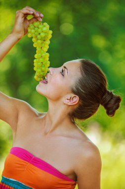 Woman with bare shoulders holding grapes clipart