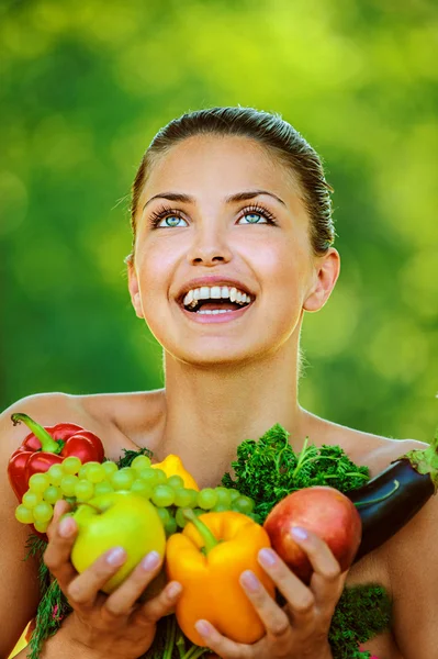 Женщина с голыми плечами держит фрукты и овощи — стоковое фото