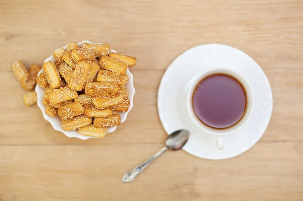 Bread sticks sprinkled with sesame seeds and cup — Stock Photo, Image
