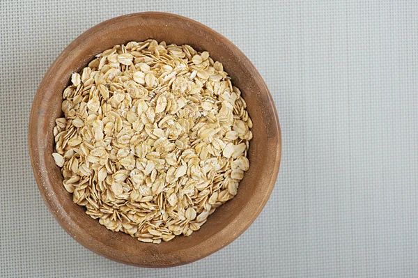 Avena enrollada en un tazón de madera sobre un paño gris . — Foto de Stock