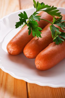 Three sausages decorated with parsley clipart