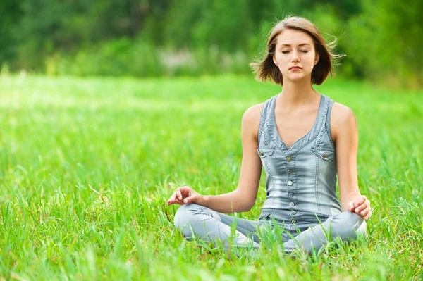 Kvinna mediterar sitter på gräset — Stockfoto