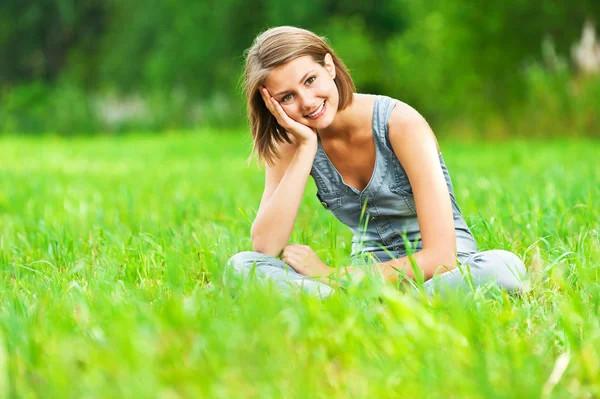 Woman sitting on green meadow with her legs crossed Royalty Free Stock Images