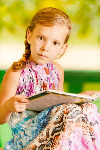 Menina senta-se livro de leitura — Fotografia de Stock