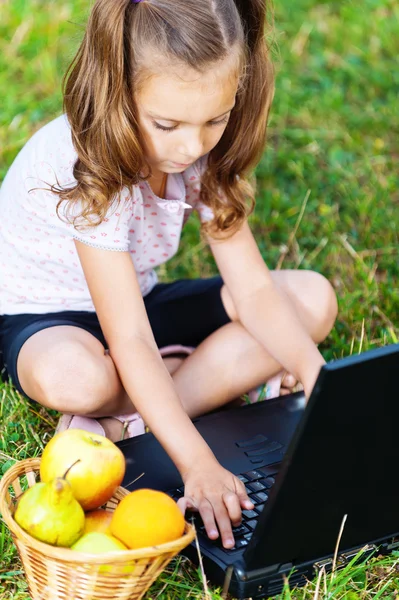 Retrato de menina (criança) com laptop e frutas — Fotografia de Stock
