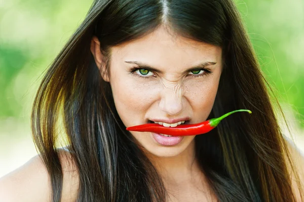 Girl with chili pepper in teeth — Stock Photo, Image